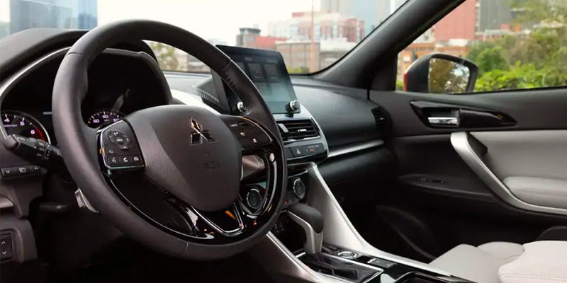 Image of the 2024 Mitsubishi Eclipse Cross front row seating with black interior, with the steering wheel in focus
