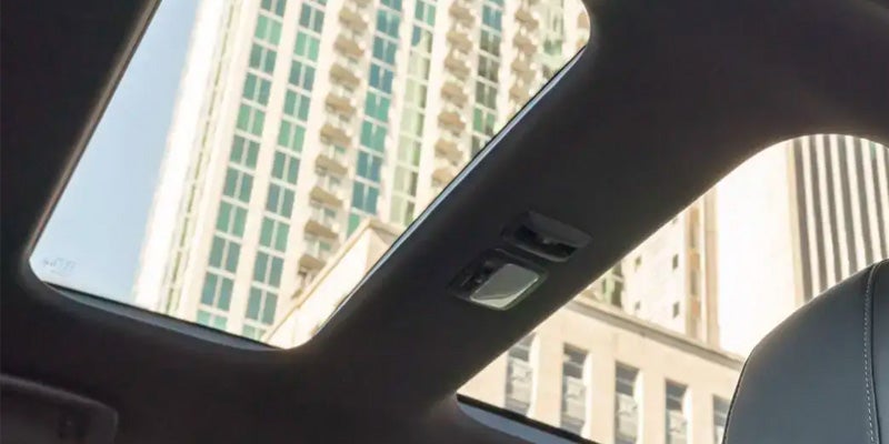 Image of the interior of the 2024 Mitsubishi Eclipse Cross with the camera angled upward through the moonroof, with a tall building pictured through the moonroof