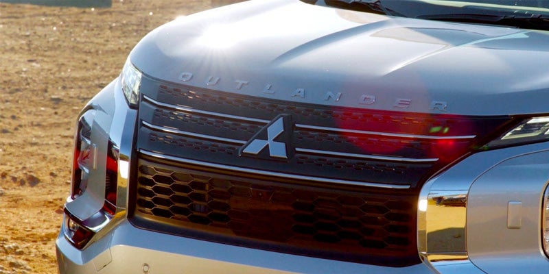 Image of a silver 2024 Mitsubishi Outlander featuring a close-up of the front grill, emblem, and headlights