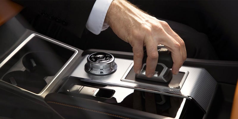 Image of the 2024 Mitsubishi Outlander interior center console with a man's hand clutching the gear shift